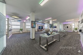 Prázdná kancelářská místnost s moderním designem, velká okna, kvalitní koberce, minimalistický interiér a LED osvětlení.