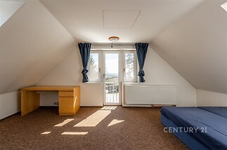 Podkrovní ložnice s velkými okny, moderní parketovou podlahou a vestavěným topením, ideální pro světlý a útulný interiér.
