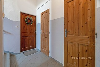 Vstupní prostor s dřevěnými dveřmi, dlažba na podlaze, světlé stěny a dekorace na dveřích.