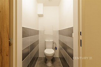 Moderní toaleta s dlažbou v neutrálních tónech, elegantní obklady a kvalitní keramika, kompaktní a čisté provedení.