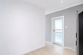 Chodba s dlažbou, moderní styl a světlé stěny, nabízí vestavěné osvětlení a bílé dveře s matným sklem.