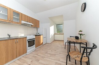 Světlá kuchyň s moderními spotřebiči, dřevěnými skříňkami a parketovou podlahou, doplněná o jídelní kout s výhledem.