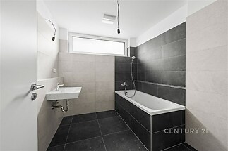 Moderní koupelna, černá a šedá dlažba, velká okna, minimalistický design, prostorný interiér, světlý prostor