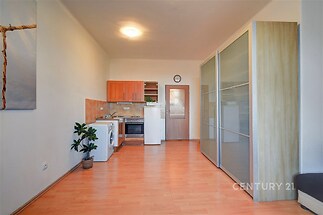 Kompaktní kuchyň s dřevěnou podlahou, světlými skříněmi a vestavěnými spotřebiči v moderním stylu.