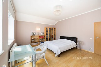 Prostorná ložnice s parketovou podlahou a velkými okny, moderní nábytek a vestavěné skříně vytvářejí světlý a útulný prostor.