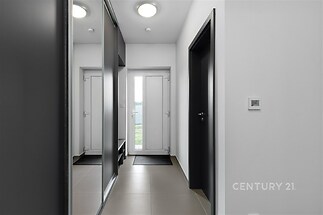 Vstupní hala s dlažbou, vestavěnými skříněmi a moderním osvětlením vytváří elegantní dojem a nabízí úložný prostor.