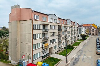 Pohled na panelový bytový dům se zrekonstruovanou fasádou a plastovými okny na klidné ulici, ideální pro rodinné bydlení.