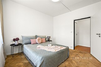 Světlá ložnice s parketovou podlahou, moderní výzdobou a minimalistickým nábytkem zvýrazňuje pohodlí a vkusný design.