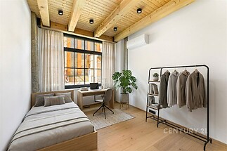 Ložnice s dřevěným stropem, parketová podlaha, velká okna, moderní styl, pokoj světlý s minimalistickým nábytkem a rostlinou.