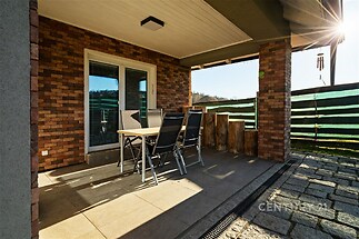 Krytá terasa s dlažbou, moderní cihlový obklad, venkovní posezení, ideální pro relaxaci a sezení na čerstvém vzduchu.