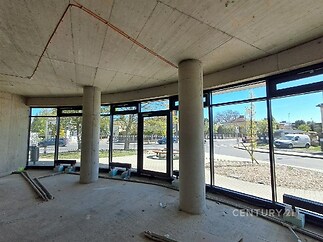 Rozestavěný interiér s velkoplošnými okny, betonovými stěnami a stropem. Světlý prostor nabízí možnost moderního designu v renovaci.