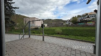 Předzahrádka s dlážděnou terasou, výhledem na zeleň a okolní krajinu, situovaná v tiché lokalitě blízko přírody, ideální pro relaxaci