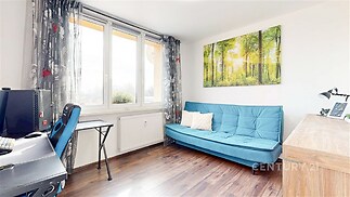 Světlý obývací pokoj s parketovou podlahou, velká okna s výhledem, moderní styl s pohodlnou pohovkou a pracovním koutem.