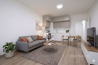 Světlý obývací pokoj s moderní kuchyní, parketová podlaha, světlý nábytek, otevřený prostor, příjemná atmosféra.