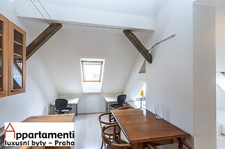 Kuchyňská jídelna s moderními prvky, dřevěným stolem a židlemi, světlá díky střešnímu oknu, parketová podlaha, šikmá střecha se starými trámy.