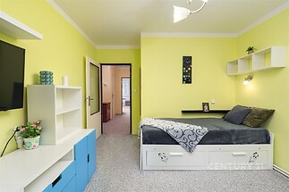 Světlá ložnice s moderním nábytkem, vestavěné skříně a koberec, vynikají světlé stěny a praktické úložné prostory.