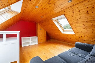 Podkrovní pokoj s dřevěnou podlahou a stropem, moderní střešní okna, světlý prostor, ideální pro úložné prostory nebo pracovní koutek.