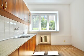 Kuchyň s parketovou podlahou, dřevěnými skříňkami a velkým oknem, v moderním stylu.