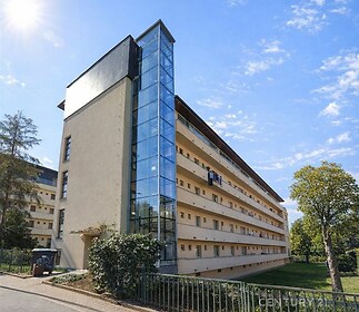 "Moderní bytový dům s proskleným výtahem, obklopený zelení, nabízí ideální bydlení. Klidná lokalita, snadný přístup do centra města."