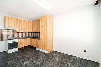 Moderní kuchyň s dlažbou, vestavěné skříně a dřevěné skříňky, světlý prostor vhodný pro rekonstrukci.