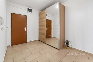 Předsíň s dlažbou a vestavěnou skříní, zrcadla na dveřích, moderní design, světlé stěny, dřevěné dveře.