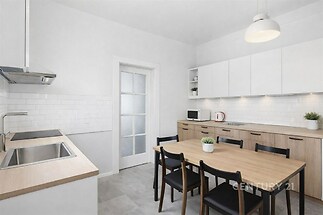 Moderní kuchyň s dřevěnými prvky, vestavěnými skříněmi a světlou dlažbou; nabízí praktický a elegantní prostor pro vaření.