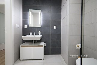 Moderní koupelna s dlažbou, stylový umyvadlový stolek a velké zrcadlo, kvalitní povrchy vytváří elegantní a čistý design