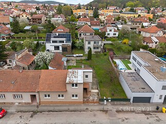 Rodinný dům s prostornou zahradou, umístěný v klidné lokalitě. Střešní panely naznačují moderní úpravy, okolní zeleň poskytuje soukromí.