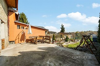 Terasa s betonovým povrchem, dřevěné posezení, zahrada s cihlovou zdí, venkovský styl, slunná lokalita