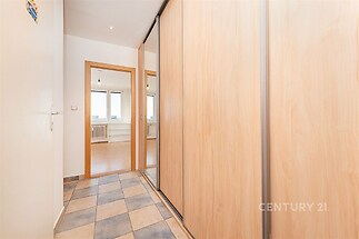 Úzká předsíň s dlažbou a vestavěnými skříněmi, moderní design, světlé dřevěné povrchy, přístup do dalších místností