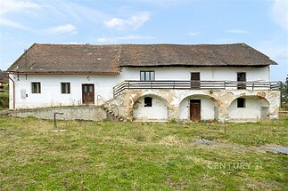 Stará venkovská budova s kamennými schody a původní omítkou, vhodná k rekonstrukci. Prostorný pozemek s možností rozvoje.