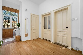 Světlá vstupní hala s parketovou podlahou, velkým oknem a moderním vybavením nabízí pohodlí a stylový design.