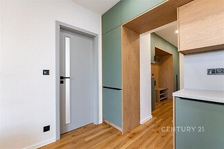 Vstupní hala s parketovou podlahou a vestavěnými skříněmi, moderní design, dřevo a pastelové povrchy vytvářejí elegantní atmosféru.