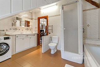 Prostorná koupelna s dlažbou, sprchovým koutem a vestavěným zrcadlem. Obsahuje i pračku, umyvadlo a WC, ideální pro rodinné bydlení.
