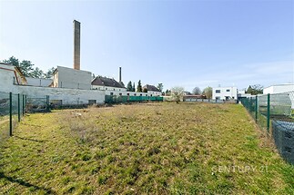 Stavební pozemek s rovinatým terénem, oplocením a výhledem na okolní zástavbu, ideální pro výstavbu rodinného domu v klidné lokalitě