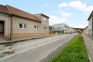 Ulice s rodinnými domy, dlážděný chodník a travnatý pás, klidná lokalita, dobrý stav budov, blízkost přírody