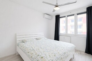 Světlá ložnice s moderním designem, parketová podlaha, vestavěná klimatizace, velká okna poskytující dostatek přirozeného světla.