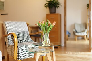 Světlý obývací pokoj s parketovou podlahou a moderním nábytkem, velká okna zajišťují příjemný přísun denního světla, stylově zařízený interiér