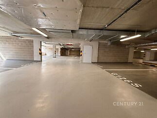 Podzemní garáž s betonovou podlahou, moderní osvětlení, vysoký strop, ideální pro parkování a skladování.