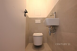 Moderní toaleta s dlažbou, minimalistické sanitární vybavení a světlé obklady vytvářejí čistý a elegantní design.