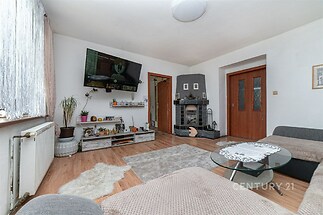 Světlý obývací pokoj s parketovou podlahou, velká okna, moderní interiér s krbem, prostorný a útulně zařízený, ideální pro rodinný život