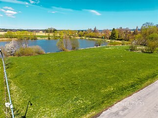 Stavební pozemek s výhledem na klidné jezero, obklopený zelení a situovaný poblíž veškeré infrastruktury, ideální pro rodinný dům.