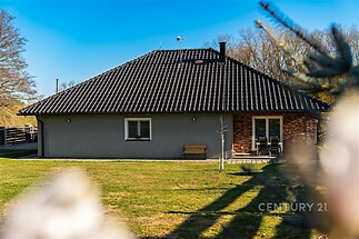 Jednopodlažní rodinný dům s šedou fasádou a černou střechou, moderní design, prostorná zahrada, klidná lokalita.