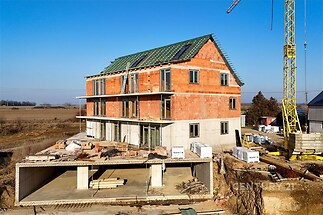 Novostavba rodinného domu ve fázi hrubé stavby, cihlová fasáda, velká okna, moderní architektura, příprava na zateplení fasády