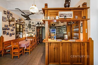 Kouzelná rustikální restaurace s dřevěným nábytkem, vystavenými fotografiemi a kachlovou podlahou nabízí atraktivní tradiční atmosféru.