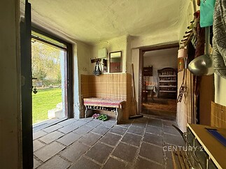 Vstupní chodba s dlažbou, otevřeným vchodem na zahradu a rustikálním stylem. Stěny s dřevěným obložením, útulný venkovský vzhled.