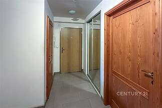 Chodba s dlažbou, vestavěnými skříněmi a dřevěnými dveřmi nabízí moderní vzhled a praktické úložné řešení.