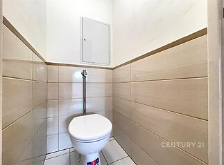 Minimalistická toaleta s keramickými obklady a dlažbou, světlé stěny, moderní úprava, úsporný design pro menší prostor.