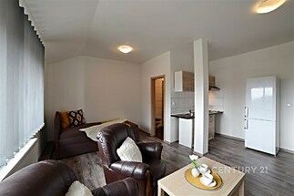 Obývací pokoj s moderní kuchyní, parketová podlaha, světlý interiér, velká okna a moderní nábytek, vhodné pro rodinné bydlení.