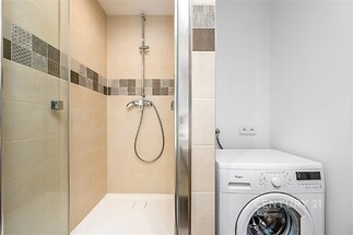 Moderní koupelna s dlažbou v hnědých tónech, sprchový kout a pračka, světlý a čistý prostor, which is a compact bathroom layout